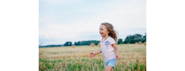 ילדה מאושרת ומשוחררת מדאגות רצה בשדה